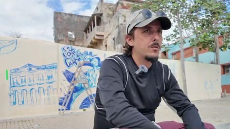 ES: Joven artista con gorra observa el inicio de un mural.
FR: Jeune artiste avec casquette observe le début d'une murale.
EN: Young artist with a cap observes the start of a mural.