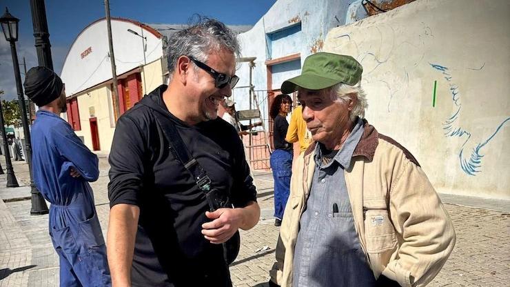ES: Dos hombres conversando en la calle junto al área de pintura.
FR: Deux hommes discutant dans la rue près de la zone de peinture.
EN: Two men talking in the street near the painting area.