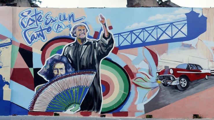 ES: Mural extenso con rostros, aves y símbolos de Cuba, Chile, Francia y Canadá.
FR: Longue murale avec visages, oiseaux et symboles de Cuba, du Chili, de France et du Canada.
EN: Long mural with faces, birds, and symbols of Cuba, Chile, France and Canada.